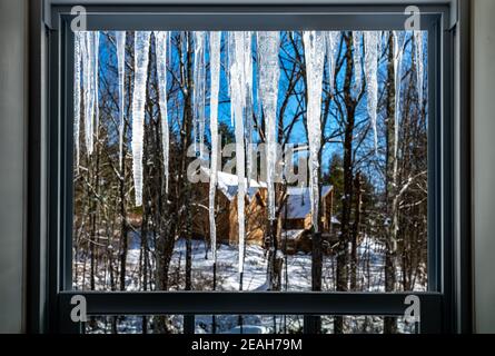 Connecticut, USA, 8. Februar 2021 - Eiskellen, die an einem verschneiten Wintertag gegen die aufgehende Sonne vom Dach eines Hauses hängen. Kredit: Enrique Shore/ Stockfoto