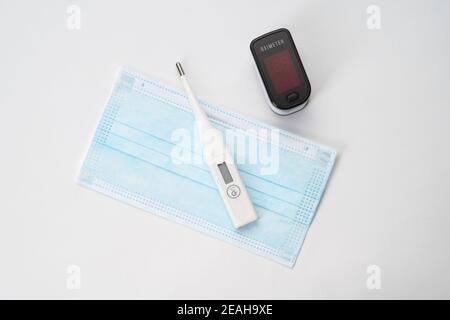 Draufsicht auf tragbares digitales Fingertipp-Oximeter, OP-Maske und Thermometer Stockfoto