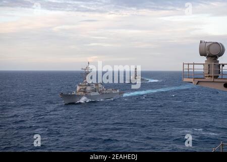 Handout Foto von – der Arleigh Burke-Klasse Lenkrakete Zerstörer USS John Finn (DDG 113), links, Und der Arleigh Burke-Klasse Lenkflugkörper Zerstörer USS Russell (DDG 59) in Formation neben dem Flugzeugträger USS Theodore Roosevelt (CVN 71) während Dual-Carrier-Operationen mit der Nimitz Carrier Strike Group im Südchinesischen Meer 9. Februar 2021. Zwei US Navy Flugzeugträger Streikgruppen begannen Operationen in den umstrittenen Gewässern des Südchinesischen Meeres am Dienstag, die neueste Show der Marine Fähigkeiten von der Biden-Regierung, wie sie verpflichtet, standhaft gegen chinesische Territo Stockfoto
