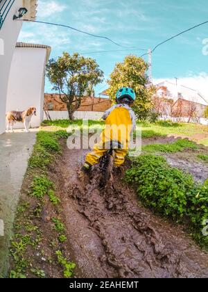 Der kleine Junge fährt mit einem blauen Fahrrad auf seinem Laufrad Helm Stockfoto