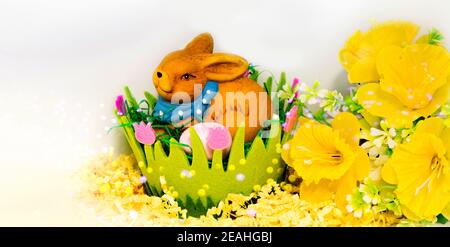 Osterhase mit Eiern in einem grünen osterkorb auf weißem Hintergrund, Blumendekoration und Platz für Text Stockfoto