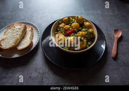 Indische Dum Aloo oder Kartoffeln in langsamem Feuer gekocht Eine Schüssel und Brotscheiben Stockfoto