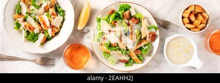 Caesar Salatpanorama, ein flaches Lay mit Soße, Croutons und Wein Stockfoto