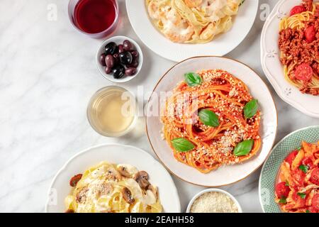 Italienisches Essen, von oben mit einem Platz für Text aufgenommen. Pasta, Oliven, Wein. Spaghetti mit Tomatensauce, Ravioli und anderen Klassikern Stockfoto