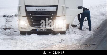 Lehrte, Deutschland. Februar 2021, 10th. Ein LKW-Fahrer versucht, seinen festgefahrenen LKW mit einer Schaufel auf dem Rastplatz lehrte-Ost zu befreien. Kredit: Julian Stratenschulte/dpa/Alamy Live Nachrichten Stockfoto