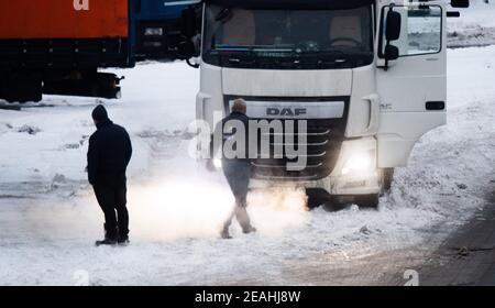 Lehrte, Deutschland. Februar 2021, 10th. Zwei Lkw-Fahrer stehen vor ihrem festgefahrenen Lkw auf dem Rastplatz lehrte-Ost. Kredit: Julian Stratenschulte/dpa/Alamy Live Nachrichten Stockfoto