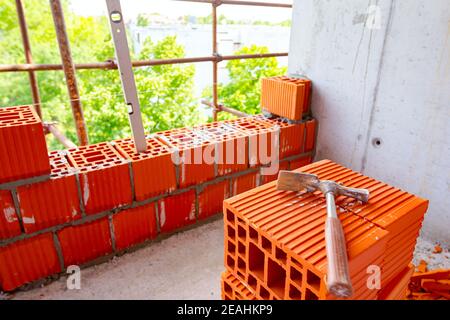 Gebrauchte Maurer Hammer auf Haufen von roten Keramikblöcken auf der Baustelle platziert. Stockfoto