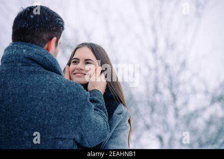 Im Freien Nahaufnahme Porträt von jungen niedlich hübsch, lächelnd paar. Modelle, die sich gegenseitig betrachten. Weihnachten, Winterurlaub, Dating-Konzept. Tageslicht Stockfoto