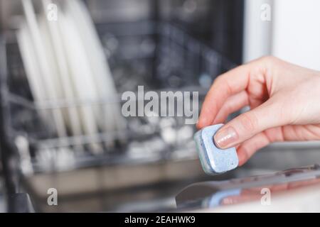 Frau, die Tablet in Spülmittelbox für Geschirrspüler legt. Stockfoto