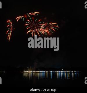 Buntes Feuerwerk mit Lichtern am See Stockfoto