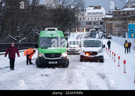 Edinburgh, Schottland, Großbritannien. Februar 2021, 10. In Großbritannien setzt sich der große Frost fort, und der schwere Schnee über Nacht und Morgen bringt den Verkehr auf vielen Straßen im Stadtzentrum zum Stillstand. PIC; Menschen frei Autos auf dem Hügel stecken. Iain Masterton/Alamy Live Nachrichten Stockfoto