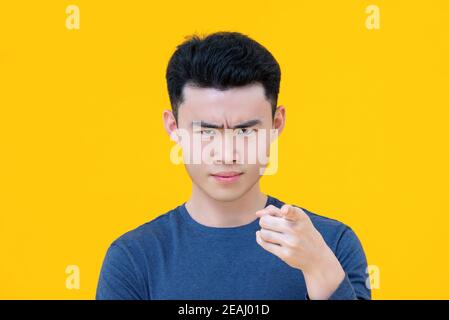 Nahaufnahme Porträt von ernst junge niedlich asiatische junge zeigen Finger auf Sie isoliert auf gelbem Hintergrund Stockfoto