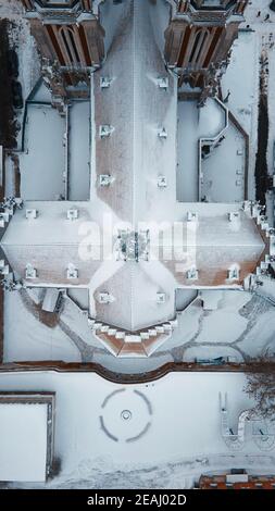 Luftaufnahme der katholischen gotischen Kirche mit Türmen unter Der Schnee Stockfoto
