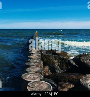 Große Steine liegen am Strand vor den Wellen. Stockfoto