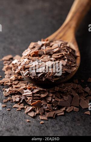 Geriebene dunkle Schokolade. Schokoladenflocken in Holzlöffel. Stockfoto