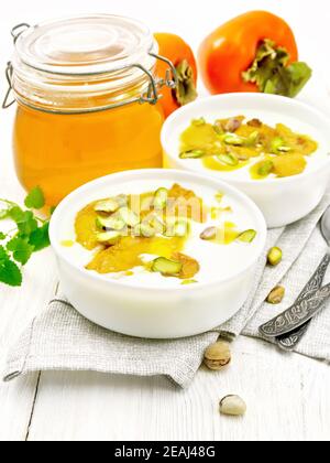 Dessert aus Joghurt und Kaki zwei Schüsseln auf hellem Holz Platine Stockfoto