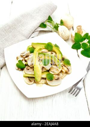 Salat aus Avocado und Champignons auf hellem Holzbrett Stockfoto