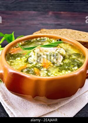 Suppe mit Couscous und Spinat in Tonschüssel auf dunkel Platine Stockfoto