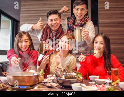 Glückliche junge Freunde, die Spaß im Hot Pot Restaurant haben Stockfoto