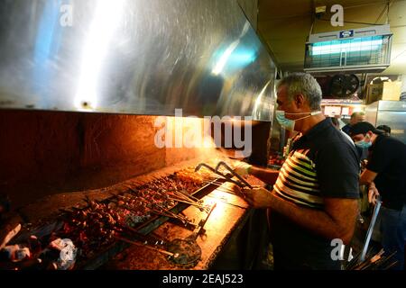 Kuwait-Stadt, Kuwait. Februar 2021, 9th. Ein Koch trägt eine Gesichtsmaske kocht Essen in einem Restaurant in Al-Mubarakiya Markt in Kuwait-Stadt, Kuwait, 9. Februar 2021. Nach einer Entscheidung der kuwaitischen Regierung, alle kommerziellen Aktivitäten zwischen 8 Uhr und 5 Uhr Ortszeit ausgesetzt sind, ausgenommen Apotheken und Lebensmittelgeschäfte, ab Februar 7 für bis zu einem Monat, der verlängert werden kann. Quelle: Asad/Xinhua/Alamy Live News Stockfoto