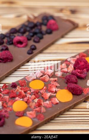 Verschiedene Arten von Schokolade mit getrockneten Früchten auf einem Holzbrett Stockfoto