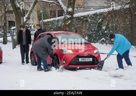 Edinburgh, Schottland, Großbritannien. Februar 2021, 10th. Aufgrund eines starken Schneefalls wurde das Stadtzentrum von Edinburgh heute Morgen zum Stillstand gebracht. Mitglieder der Öffentlichkeit helfen einem Fahrer im Schnee stecken. Kredit: Lorenzo Dalberto/Alamy Live Nachrichten Stockfoto