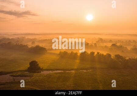 Naturlandschaft mit Sonne aufgehen über Land bedeckt mit Nebel. Stockfoto