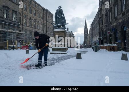 Edinburgh, Schottland, Großbritannien. Februar 2021, 10th. Aufgrund eines starken Schneefalls wurde das Stadtzentrum von Edinburgh heute Morgen zum Stillstand gebracht. Ein Mann wird mit einem Spaten gesehen, der einen Weg in der Innenstadt von Edinburgh freimacht. Kredit: Lorenzo Dalberto/Alamy Live Nachrichten Stockfoto