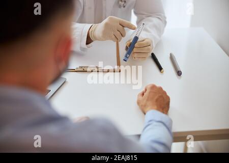 Fokussiertes Bild von Arztarmen mit Medikament in der Hand Über dem weißen Schreibtisch Stockfoto