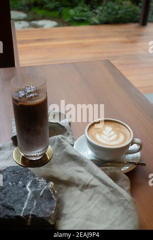 Heißer Kaffee und Eiskaffee auf hölzernen Tisch Stockfoto