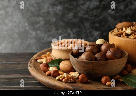 Tablett mit Schüsseln mit verschiedenen Nüssen auf Holzhintergrund Stockfoto