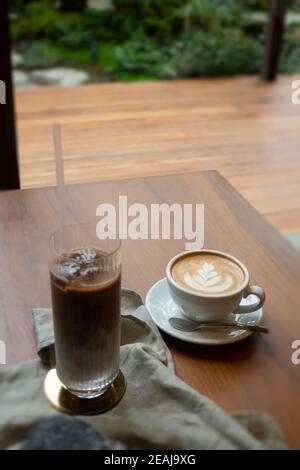 Heißer Kaffee und Eiskaffee auf hölzernen Tisch Stockfoto