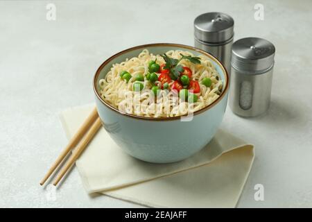 Konzept des leckeren Essens mit Schüssel Nudeln auf weiß Strukturierter Hintergrund Stockfoto