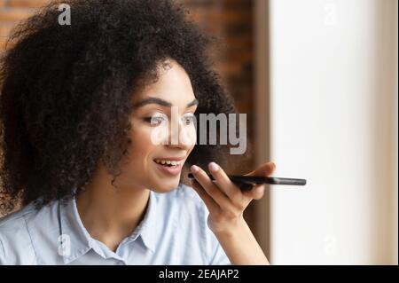 Nahaufnahme einer jungen Geschäftsfrau mit gemischter Rasse oder einer Unternehmerin mit afro Frisur, die ein Mobiltelefon hält, im Gespräch chattet und eine Aufnahme macht Stockfoto