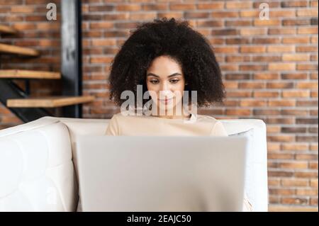 Porträt einer jungen Geschäftsfrau mit gemischter Rasse oder Freiberuflerin Mit Afro Frisur im Liegen auf der Couch und Arbeiten am Projekt Stockfoto