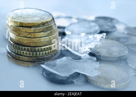 Im Eis eingefrorene Euro-Münzen. Gefrorenes Geld, Euro im Eis mit Eiszapfen Stockfoto