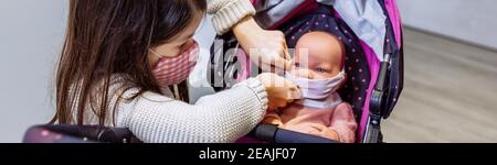 Mädchen mit Gesichtsmaske Putting Maske auf ihre Baby-Puppe Stockfoto