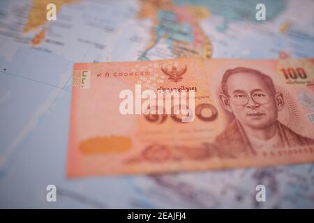 Hundert Thai Baht Bill unter Thailand auf einem bunten Und verschwommene Asien-Karte Stockfoto