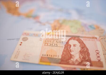 Zehntausend kolumbianische Pesos Rechnung unter Kolumbien auf einem bunten Und verschwommene Karte Stockfoto