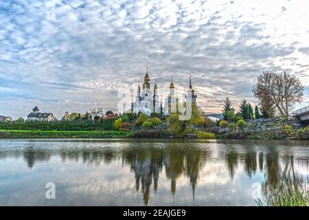 Das Wasser des Flusses Rostavitsya spiegelt die christlich-orthodoxe Kirche St. Eugen und mit einem Glockenturm und einem Landschaftspark im Dorf. Buki, Ukraine Stockfoto