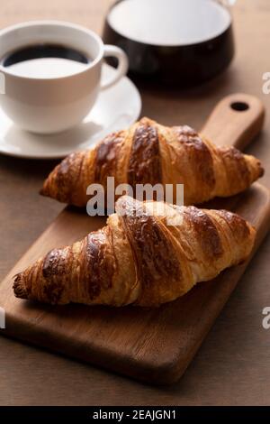 Croissants und Kaffee auf einem Holzbrett Stockfoto