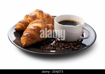 Ein Croissant, Kaffee und Kaffeebohnen in einem schwarzen Gericht auf weißem Hintergrund Stockfoto