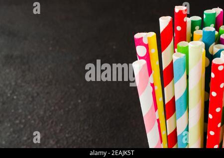 Bunte Papierhalme in verschiedenen Farben für Cocktails und Drinks auf dunklem Hintergrund. Stockfoto