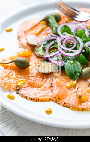 Lachs Carpaccio und Rucola Salat mit Zwiebeln und Kapern Stockfoto