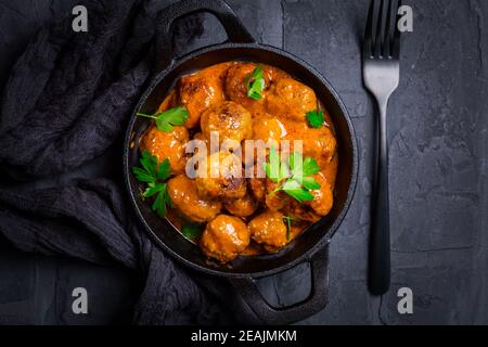 Fleischbällchen mit Tomatensauce in schwarzer Pfanne Stockfoto