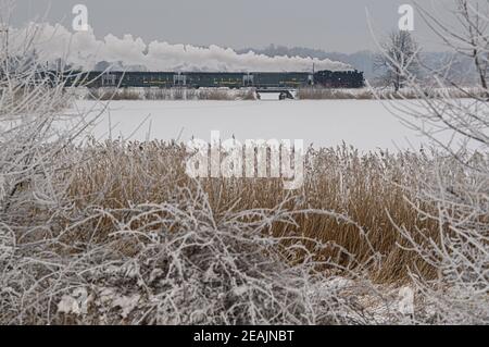 Moritzburg, Deutschland. Februar 2021, 10th. Die Lößnitzgrundbahn verläuft über einen Damm in der verschneiten Winterlandschaft am Dippelsdorfer Teich. Die Schmalspurbahn, die im Volksmund als "Lößnitzdackel" oder "Grundwurm" bekannt ist, hat eine Spurweite von 750 Millimetern und verläuft von Radebeul nach Radeburg. Die Züge sind derzeit spärlich befahren, ebenso wie die der anderen Bimmelbahnen in Sachsen. Aufgrund der Einschränkungen von Corona überschreiten die Züge, die hauptsächlich von Touristen genutzt werden, derzeit nicht die Kapazität von 25 Prozent. Quelle: Robert Michael/dpa-Zentralbild/dpa/Alamy Live News Stockfoto