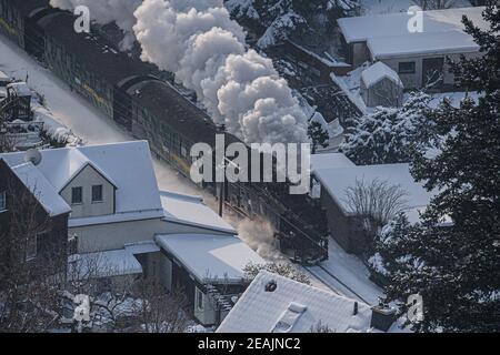 Radebeul, Deutschland. Februar 2021, 10th. Die Lößnitzgrundbahn verläuft durch Radebeul in der verschneiten Winterlandschaft. Die Schmalspurbahn, im Volksmund "Lößnitzdackel" oder "Grundwurm" genannt, hat eine Spurweite von 750 Millimetern und verläuft von Radebeul nach Radeburg. Die Züge sind derzeit spärlich befahren, ebenso wie die der anderen Bimmelbahnen in Sachsen. Aufgrund der Einschränkungen von Corona überschreiten die Züge, die hauptsächlich von Touristen genutzt werden, derzeit nicht die Kapazität von 25 Prozent. Quelle: Robert Michael/dpa-Zentralbild/dpa/Alamy Live News Stockfoto