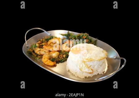 Garnelen oder Garnelen mit Basilikumblättern, Spiegeleier über Reis anbraten. Thailändisches Essen Stockfoto