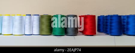 Farbige Fäden für die Nähmaschine auf dem Regal, Banner Stockfoto