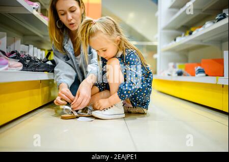 Mutter und kleines Baby versuchen auf Schuhe im Geschäft Stockfoto